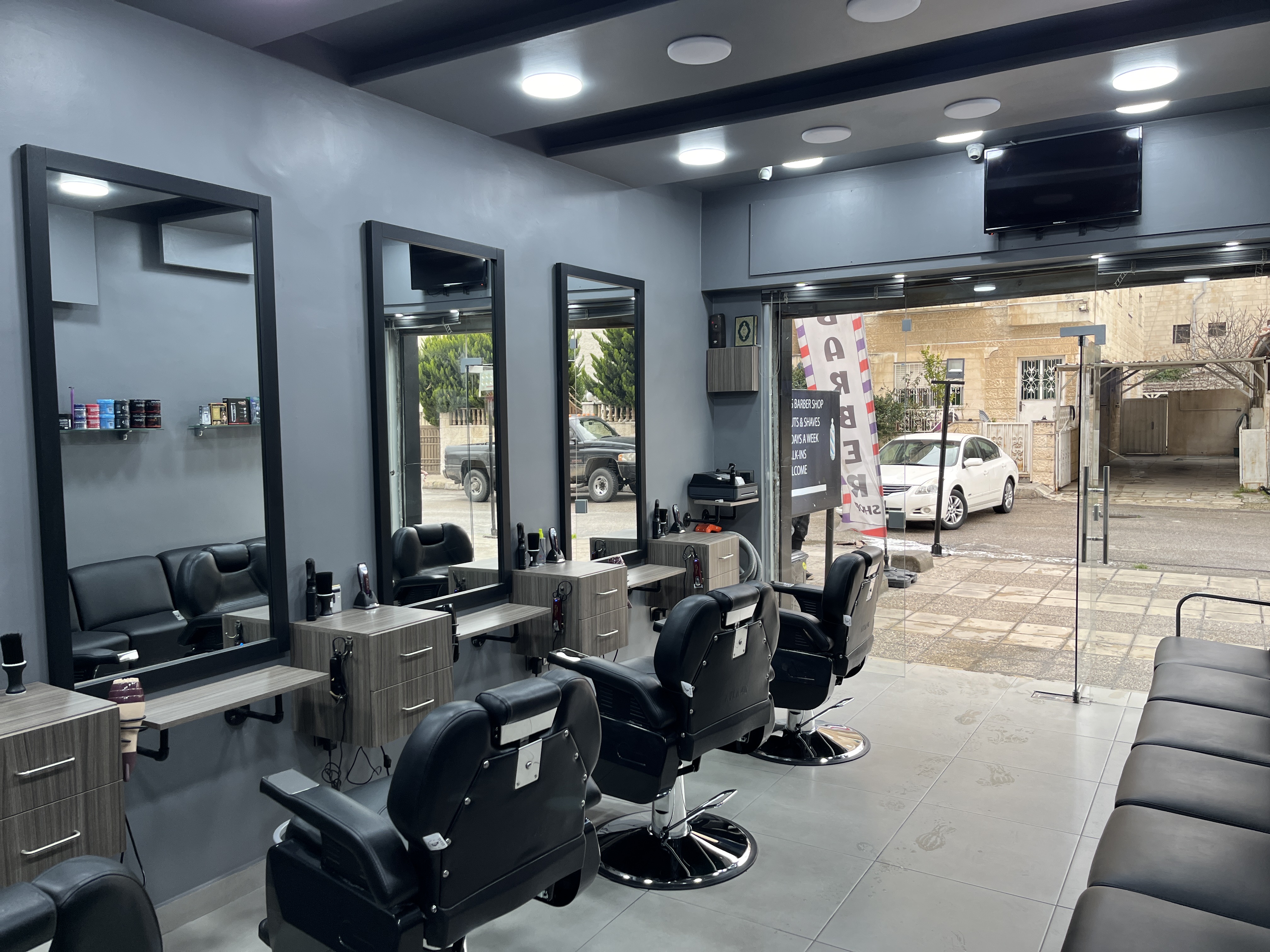 Makkawi's Barber Shop interior with black leather chairs, mirrors and an open street-level glass front