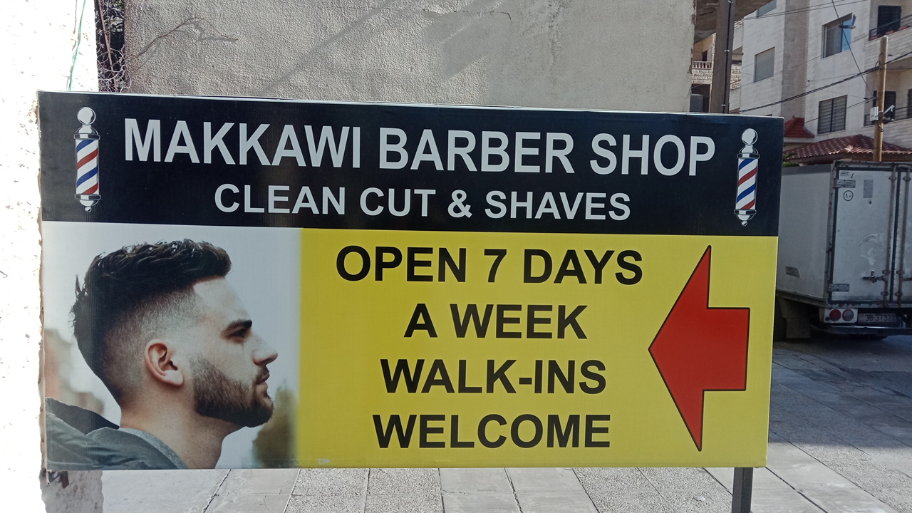 Directional sign reading Makkawi Barber Shop, open 7 days a week, walk-ins welcome